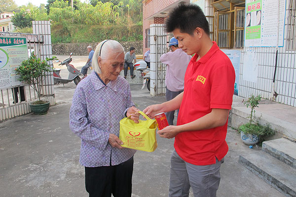 村民接过王老吉大健康员工亲手送上的王老吉和爱心药包，激动之情溢于言表