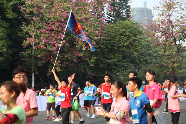 身穿着红色王老吉T恤的王老吉长跑健将们在人潮中举着大旗引领着队伍冲刺